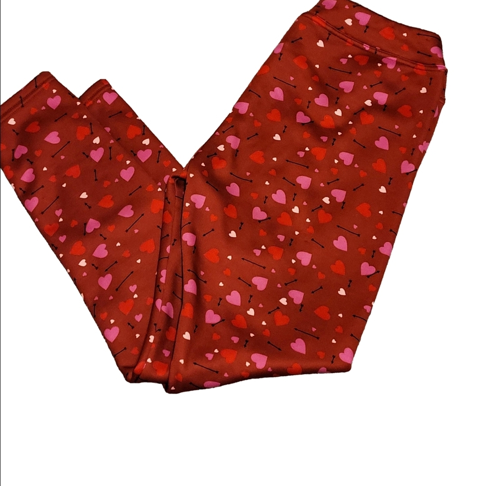Vibrant red leggings featuring a playful pattern of hearts and arrows.